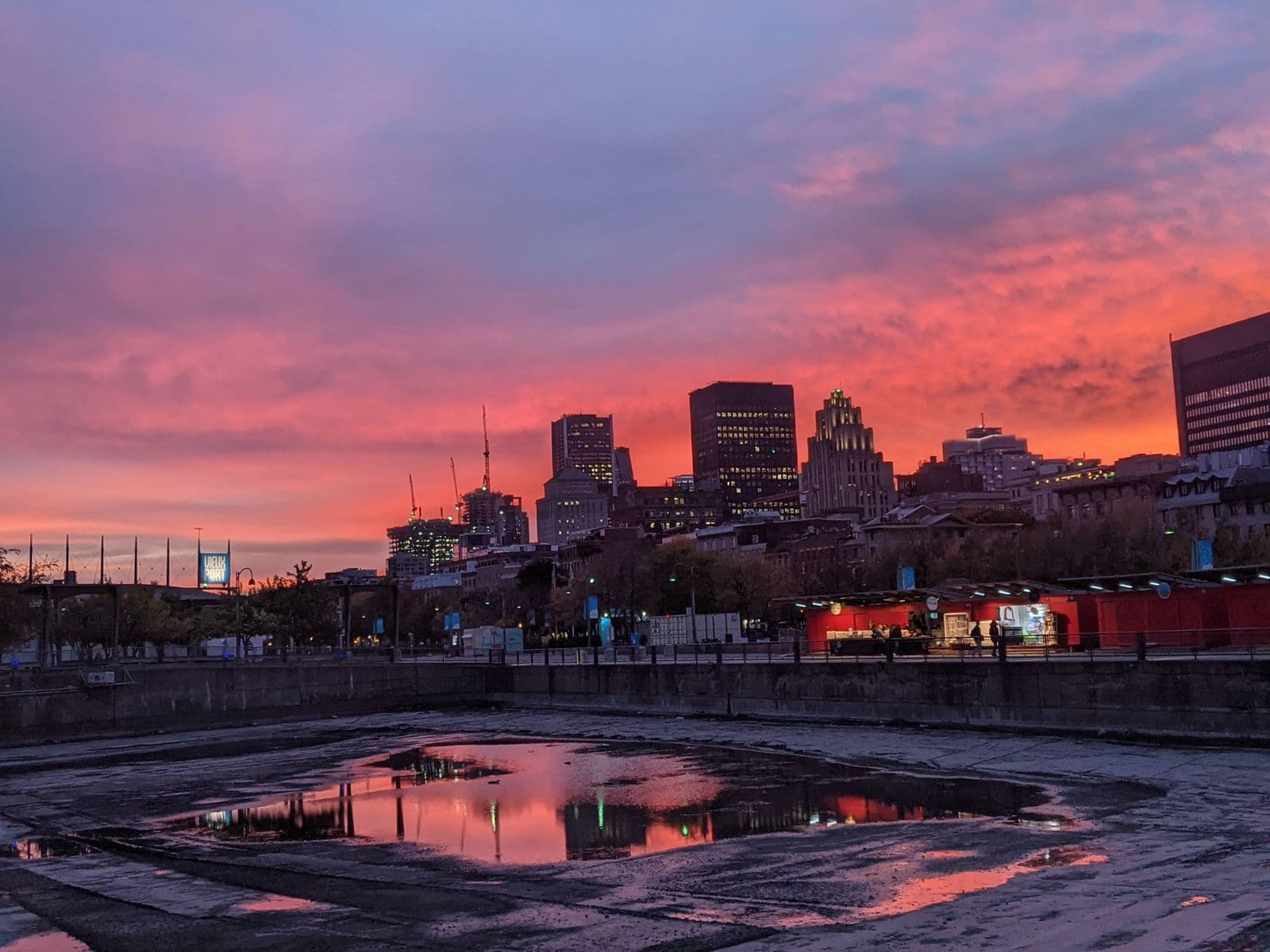 Le Vieux-Port de Montréal au coucher du soleil, les tours du centre-ville se détachant sur un ciel rouge.