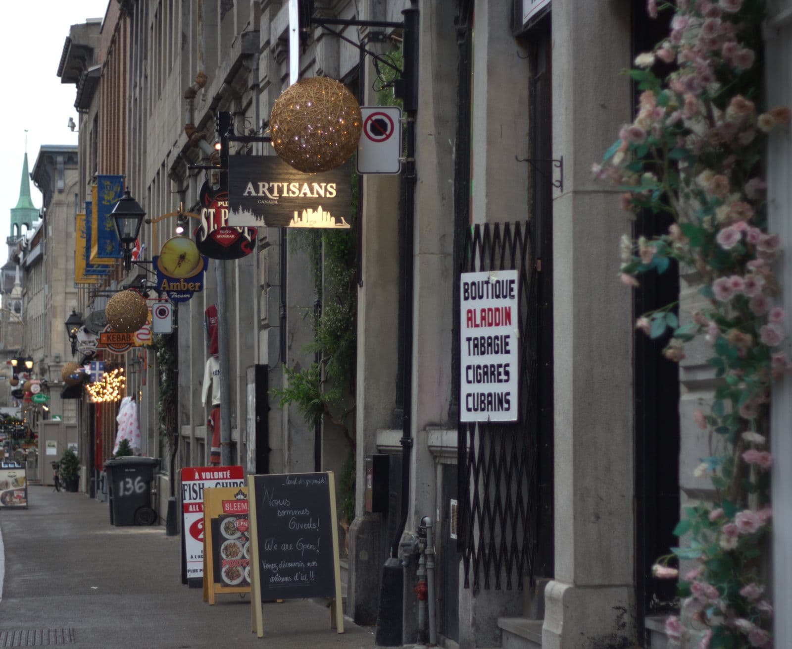 Une rue pavée du Vieux-Montréal bordée d’enseignes de boutiques et de restaurants.