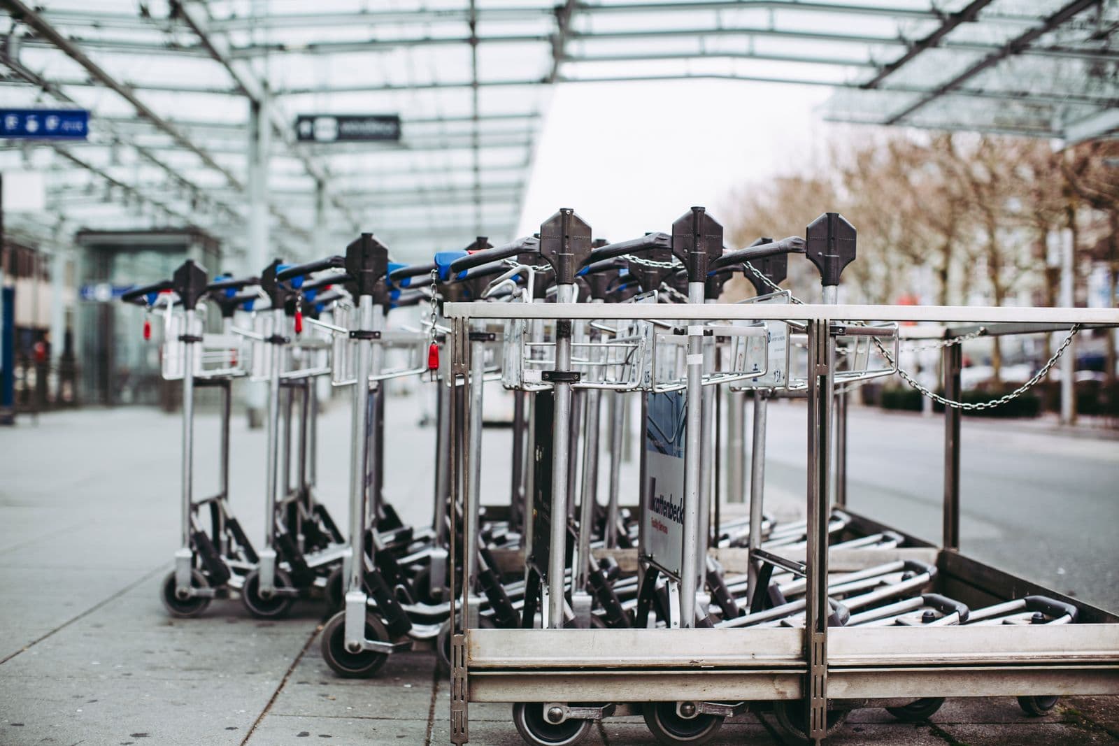 Des chariots à bagages alignés devant une aérogare.
